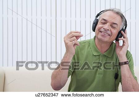 Stock Photo - Domestic Life, a senior man listening to music with eyes closed and smiling. Fotosearch