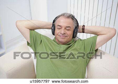 Stock Photo - Domestic Life, a senior man lying on sofa and listening music with eyes closed. Fotosearch