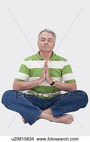 Picture - Domestic Life, a senior man making lotus position with eyes closed. Fotosearch