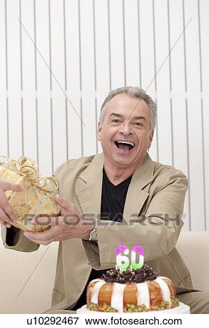 Domestic Life, a senior man receiving a gift and smiling happily View Large Photo Image Stock Photo - Domestic Life, a senior man receiving a gift and smiling happily. Fotosearch