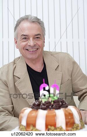 Domestic Life, a senior man sitting with birthday cake and smiling happily View Large Photo Image Stock Image - Domestic Life, a senior man sitting with birthday cake and smiling happily. Fotosearch