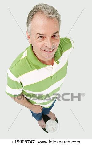 Domestic Life, a senior man standing on the weight scale and looking up with smile View Large Photo Image Stock Photo - Domestic Life, a senior man standing on the weight scale and looking up with smile. Fotosearch