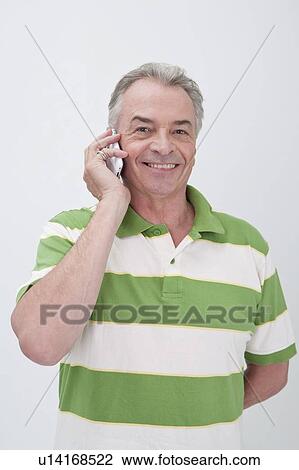 Stock Image - Domestic Life, a senior man standing and using mobile phone with smile. Fotosearch
