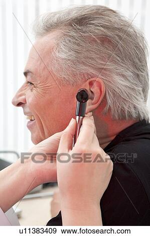 Stock Photo - Domestic Life, a senior man taking medical exam and looking away with smile. Fotosearch