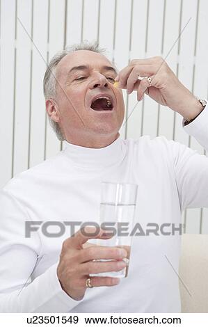 Domestic Life, a senior man taking medicine with a glass of water View Large Photo Image Stock Photo - Domestic Life, a senior man taking medicine with a glass of water. Fotosearch