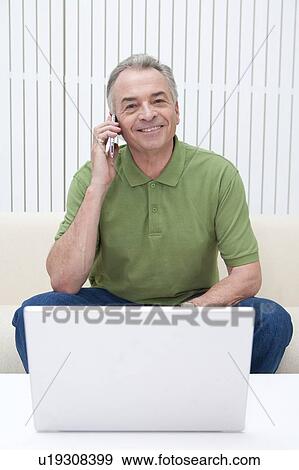 Domestic Life, a senior man using mobile phone and smiling at the camera View Large Photo Image Stock Photo - Domestic Life, a senior man using mobile phone and smiling at the camera. Fotosearch