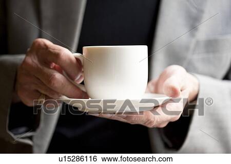 Domestic Life, Close-up of human hands holding a cup and saucer View Large Photo Image Stock Photograph - Domestic Life, Close-up of human hands holding a cup and saucer. Fotosearch