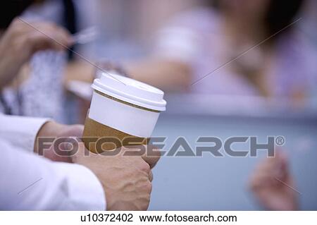 Stock Image - Close-up of hands holding a cup of coffee. Fotosearch