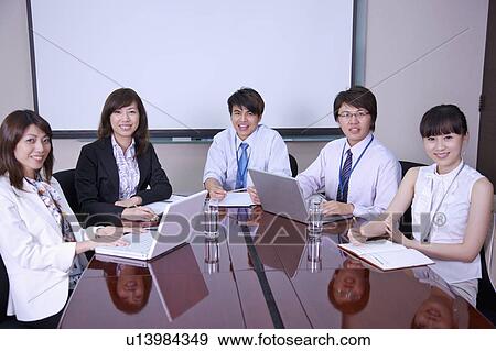 Stock Photo - Colleagues having a meeting and smiling at the camera. Fotosearch