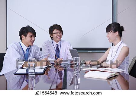 Stock Photo - Colleagues talking in office and smiling together. Fotosearch