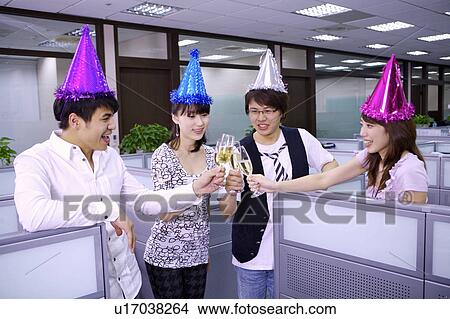 Picture - Four colleagues wearing party hats and celebrating together. Fotosearch