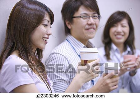 Three colleagues holding coffee and smiling together View Large Photo Image Stock Photograph - Three colleagues holding coffee and smiling together. Fotosearch