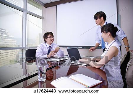 Stock Image - Three colleagues talking in office with smile. Fotosearch