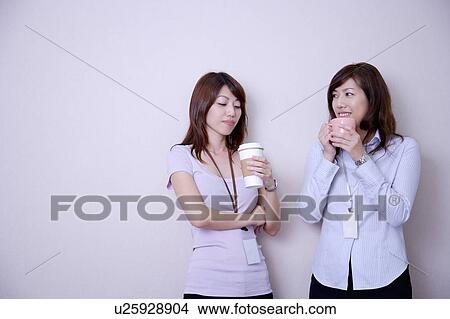 Two women drinking coffee at coffee break and smiling View Large Photo Image Picture - Two women drinking coffee at coffee break and smiling. Fotosearch