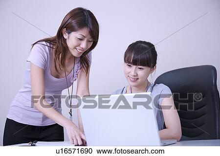 Stock Image - Two women looking at the laptop with smile together. Fotosearch