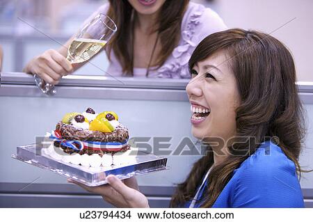 Picture - Woman holding a cake and laughing happily. Fotosearch