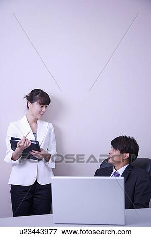 Young man and woman talking in office and smiling at each other View Large Photo Image Stock Photo - Young man and woman talking in office and smiling at each other. Fotosearch