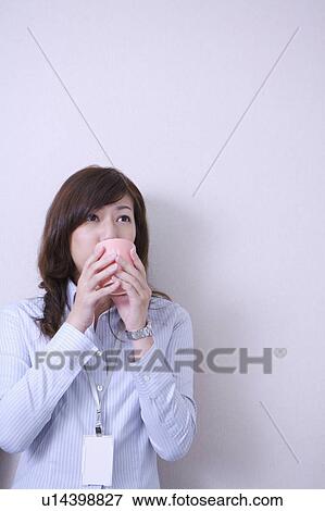Young woman holding a cup and drinking View Large Photo Image Stock Photo - Young woman holding a cup and drinking. Fotosearch
