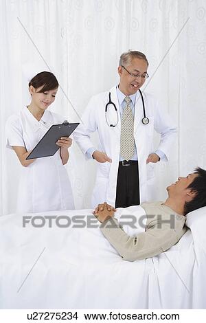 Picture - Doctor and nurse looking after the patient. Fotosearch