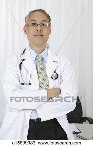 Stock Image - Doctor standing with arms crossed and looking at the camera. Fotosearch