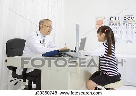 Stock Photo - Doctor talking with little girl and writing. Fotosearch