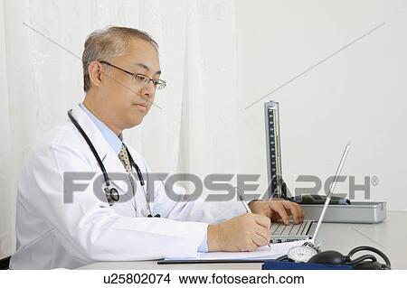 Doctor writing on the clipboard and looking down View Large Photo Image Picture - Doctor writing on the clipboard and looking down. Fotosearch