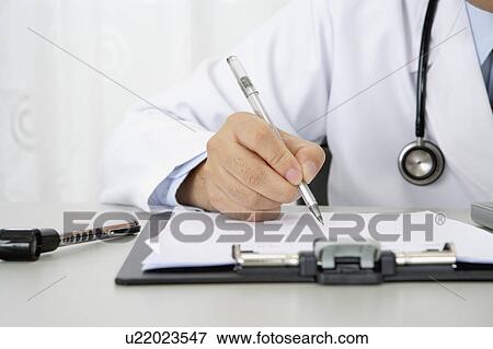 Stock Photo - Doctor writing on the clipboard. Fotosearch