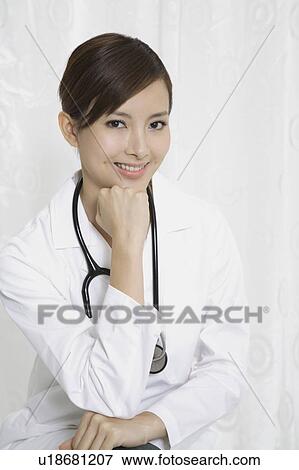 Stock Photo - Female doctor smiling at the camera with hand on chin. Fotosearch