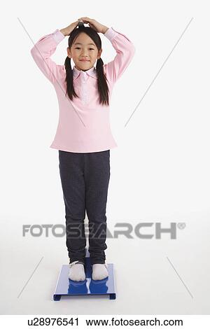Stock Image - Little girl measuring the height and smiling. Fotosearch