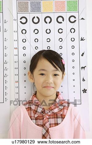 Stock Photo - Little girl standing before eye chart and smiling. Fotosearch