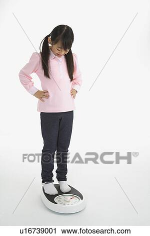 Stock Image - Little girl standing on the weight scale. Fotosearch
