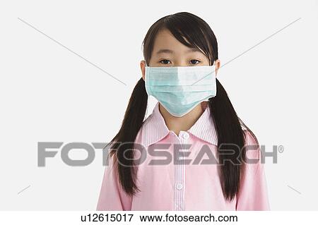 Stock Photo - Little girl wearing a surgical mask and looking at the camera. Fotosearch