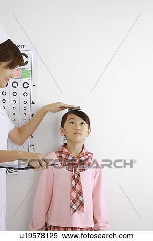 Young nurse measuring little girl's height and holding clipboard View Large Photo Image Stock Photography - Young nurse measuring little girl's height and holding clipboard. Fotosearch