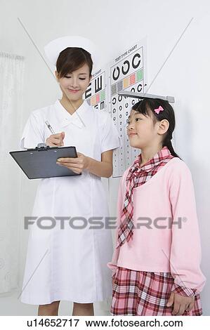 Stock Photo - Young nurse writing on clipboard for little girl's height. Fotosearch