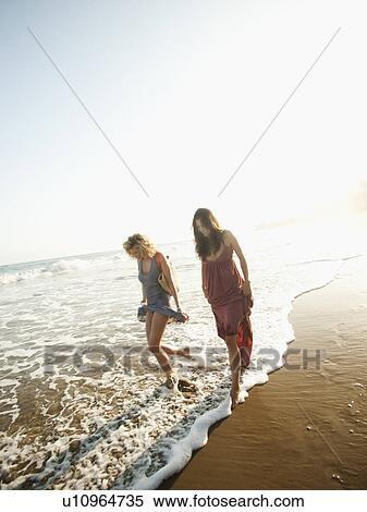 Stock Photography - Attractive young woman walking on sandy beach. Fotosearch