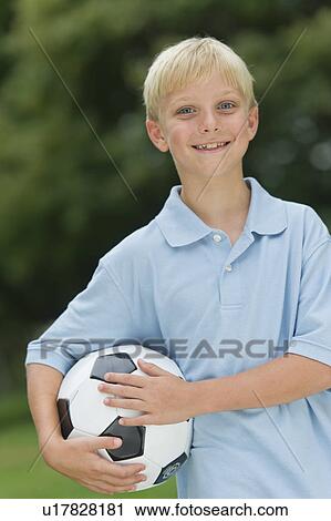Stock Image - Boy (10-11) holding soccer ball. Fotosearch
