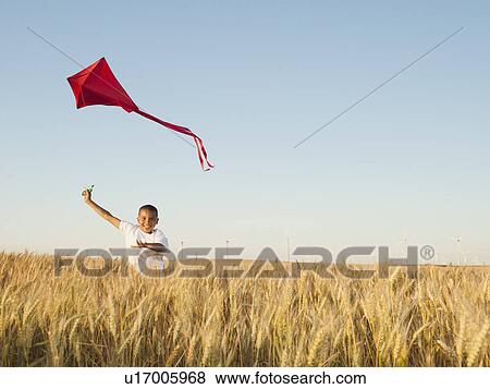 Boy (10-11) playing with kite in wheat field View Large Photo Image Stock Photo - Boy (10-11) playing with kite in wheat field. Fotosearch