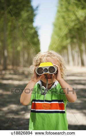 Boy (2-3) looking through binoculars in tree farm View Large Photo Image Picture - Boy (2-3) looking through binoculars in tree farm. Fotosearch