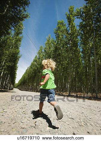 Stock Image - Boy (2-3) running up country road. Fotosearch