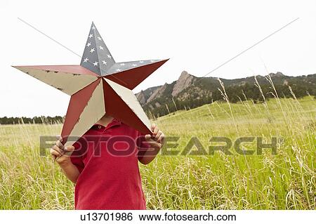 Stock Photograph - Boy (6-7) playing with star with American flag pattern. Fotosearch