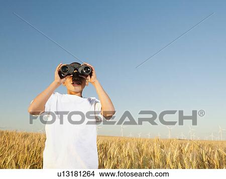 Boy (8-9) standing in wheat field, looking through binoculars View Large Photo Image Picture - Boy (8-9) standing in wheat field, looking through binoculars. Fotosearch