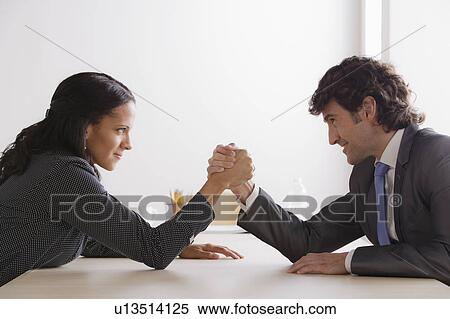 Stock Photography - Business man and business woman armwrestling. Fotosearch
