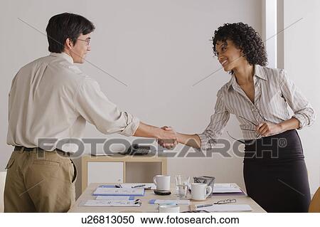 Stock Image - Businessman and businesswoman handshake during meeting. Fotosearch