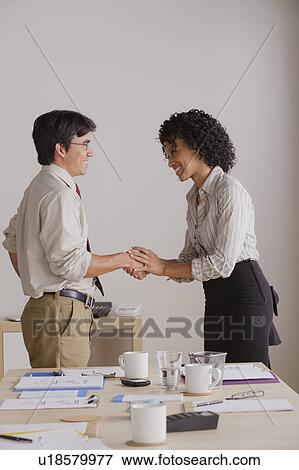 Stock Photo - Businessman and businesswoman handshake during meeting. Fotosearch