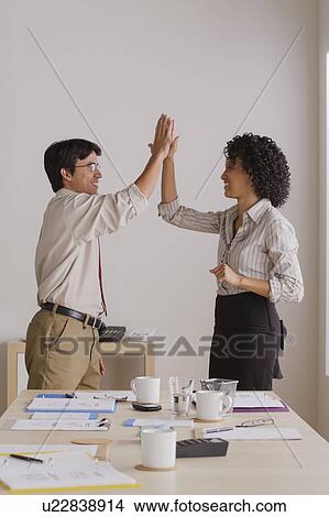 Picture - Businessman and businesswoman high fiving. Fotosearch