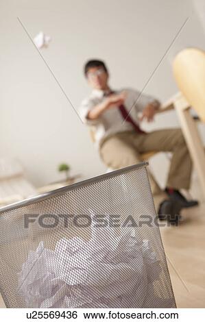Businessman tossing ball of paper into wastebasket View Large Photo Image Stock Photograph - Businessman tossing ball of paper into wastebasket. Fotosearch
