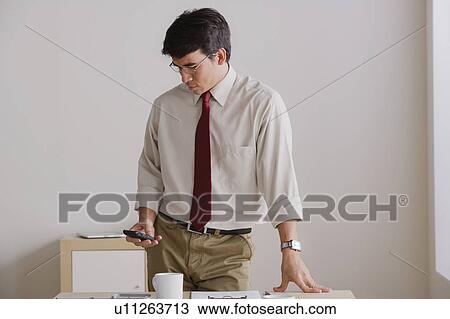 Businessman using cell phone in office View Large Photo Image Stock Image - Businessman using cell phone in office. Fotosearch
