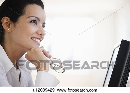 Stock Photo - Businesswoman daydreaming at desk in office. Fotosearch