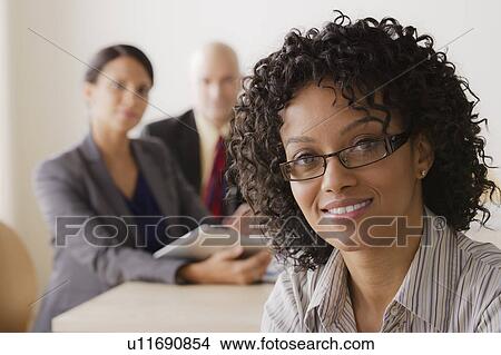 Picture - Businesswoman looking at camera, business team in background. Fotosearch