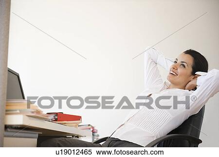 Businesswoman relaxing at desk in office View Large Photo Image Stock Photography - Businesswoman relaxing at desk in office. Fotosearch